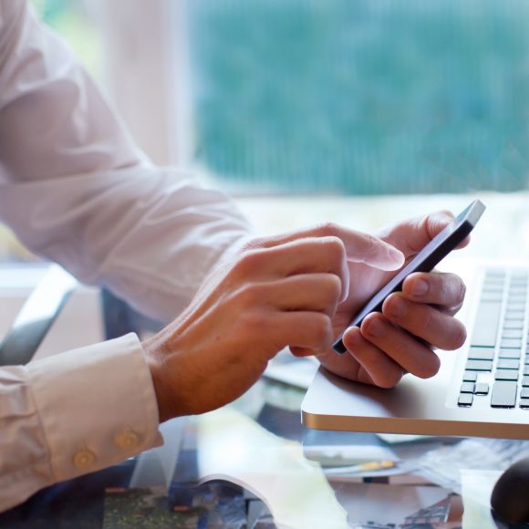 Office worker with a notebook PC looking at a smartphone